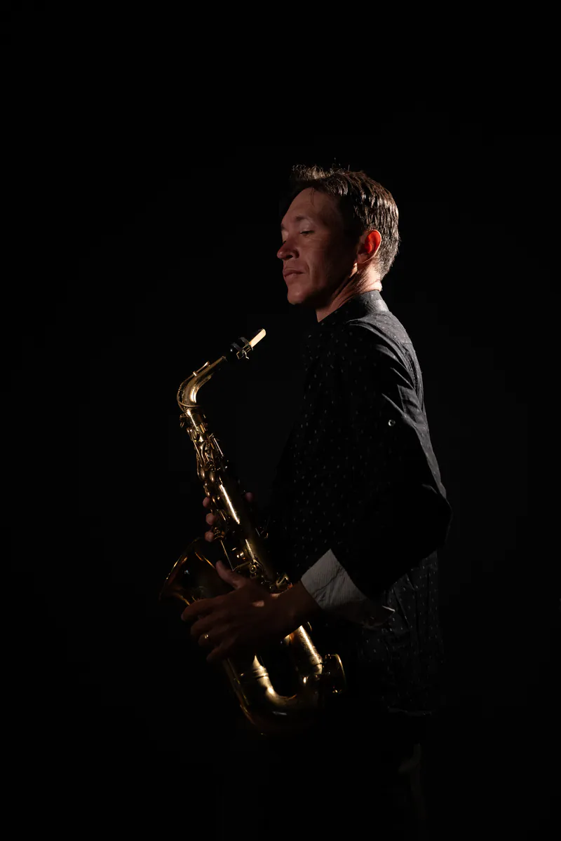 Zirano in half-light, looking at his saxophone