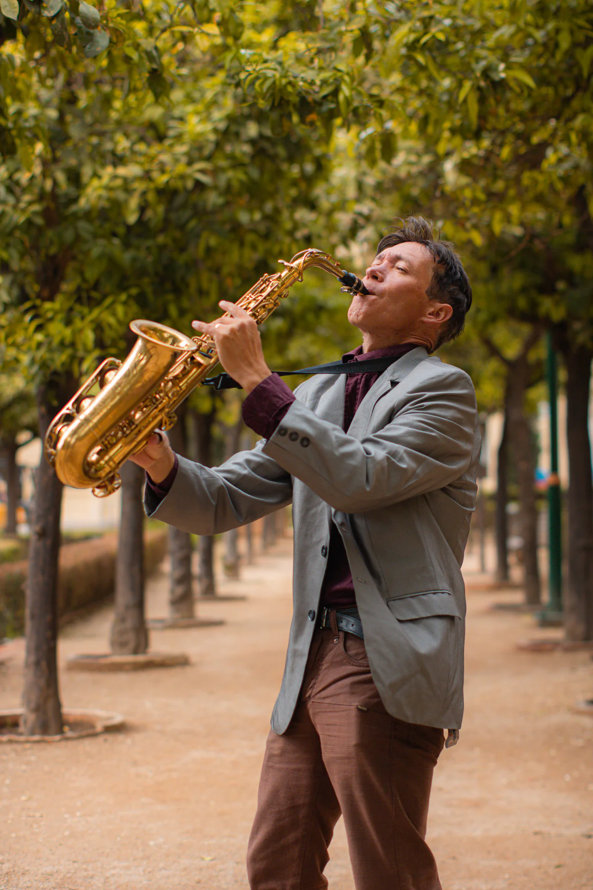 Zirano tocando el saxofón en un paseo arbolado