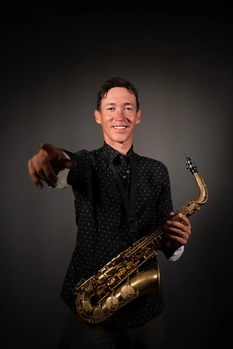 Zirano sonriendo y señalando a cámara con el saxofón en la mano