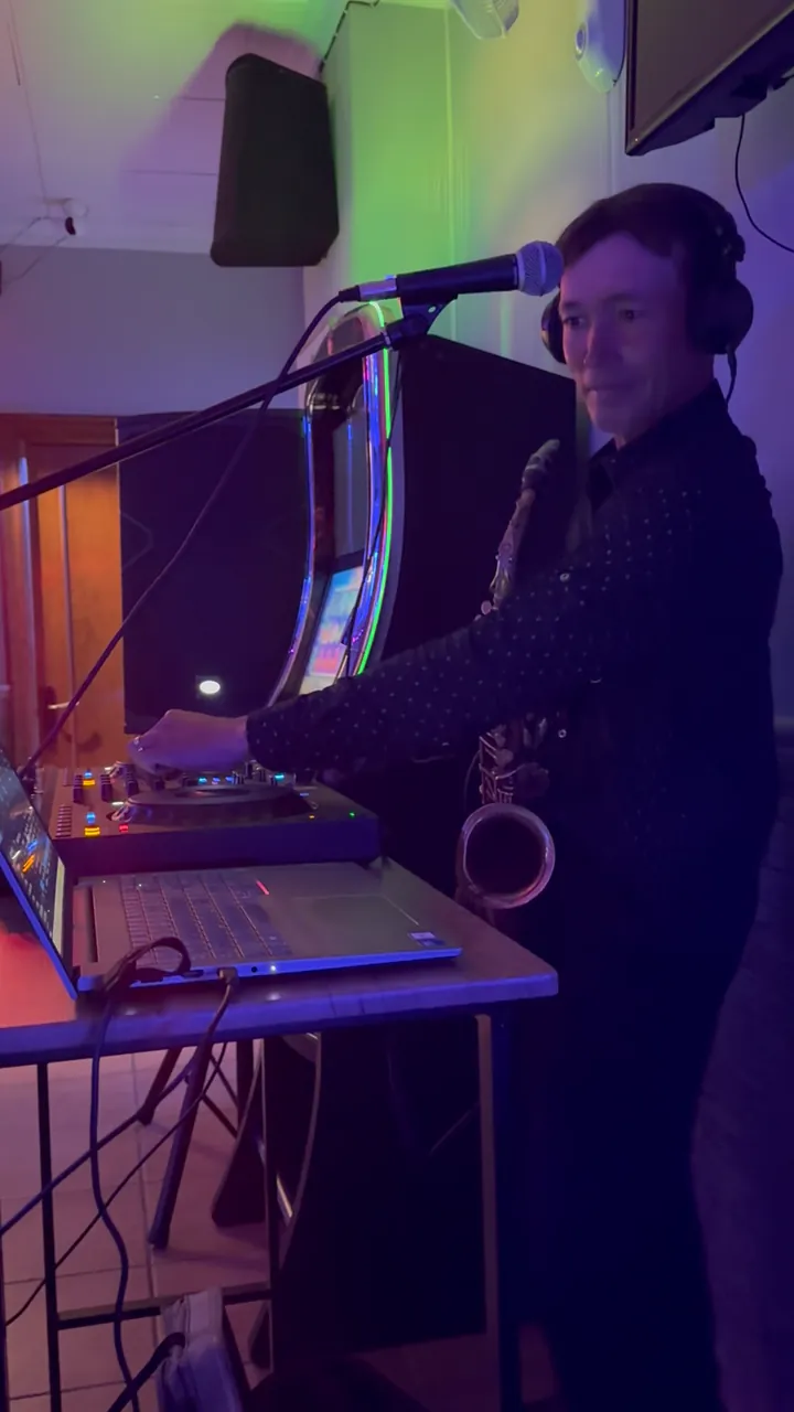 Zirano pinchando con cascos, con el saxofón colgado al cuello y un micrófono delante