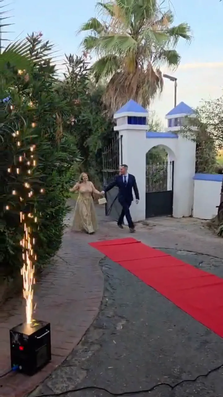 Entrada de una fiesta de cumpleaños con alfombra roja, luces y una fuente de chispas en el suelo